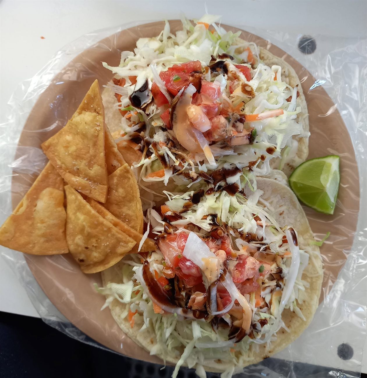 Dos tacos capeados con col, jitomate y salsa, con limón