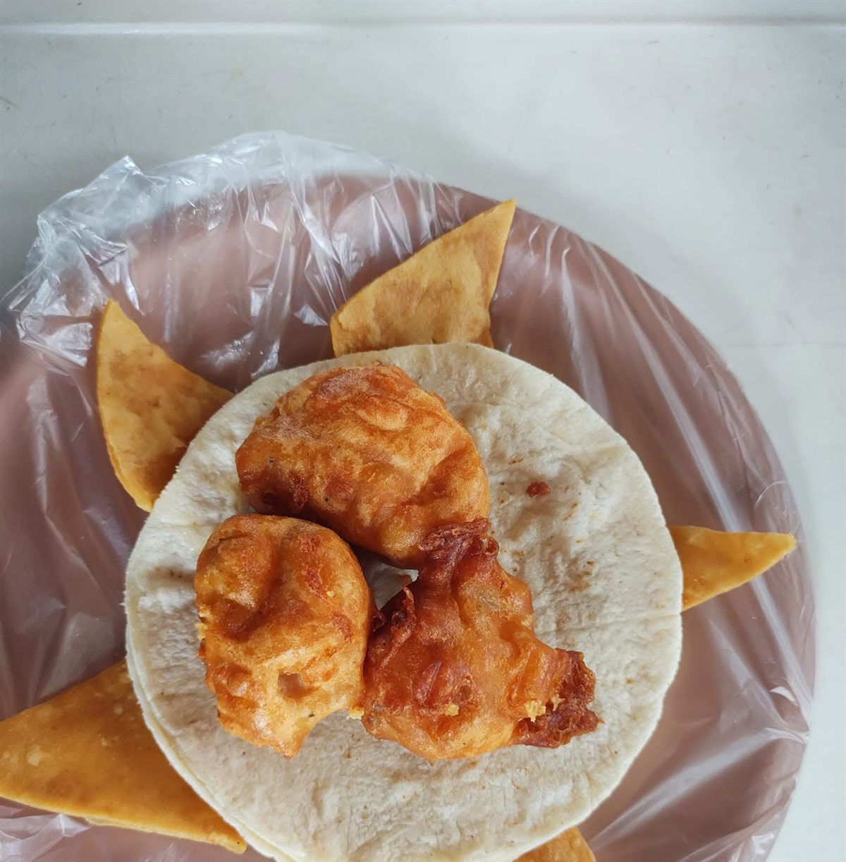 Piezas de pescado capeado sobre tortilla con totopos