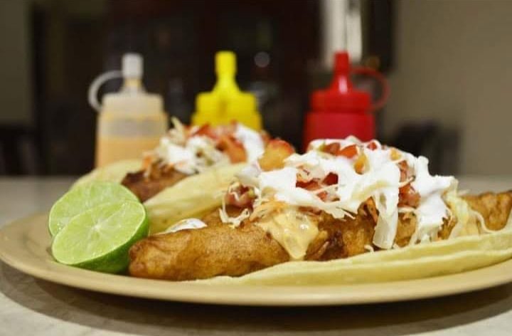 Tacos de pescado capeado con crema, col y limón en un plato