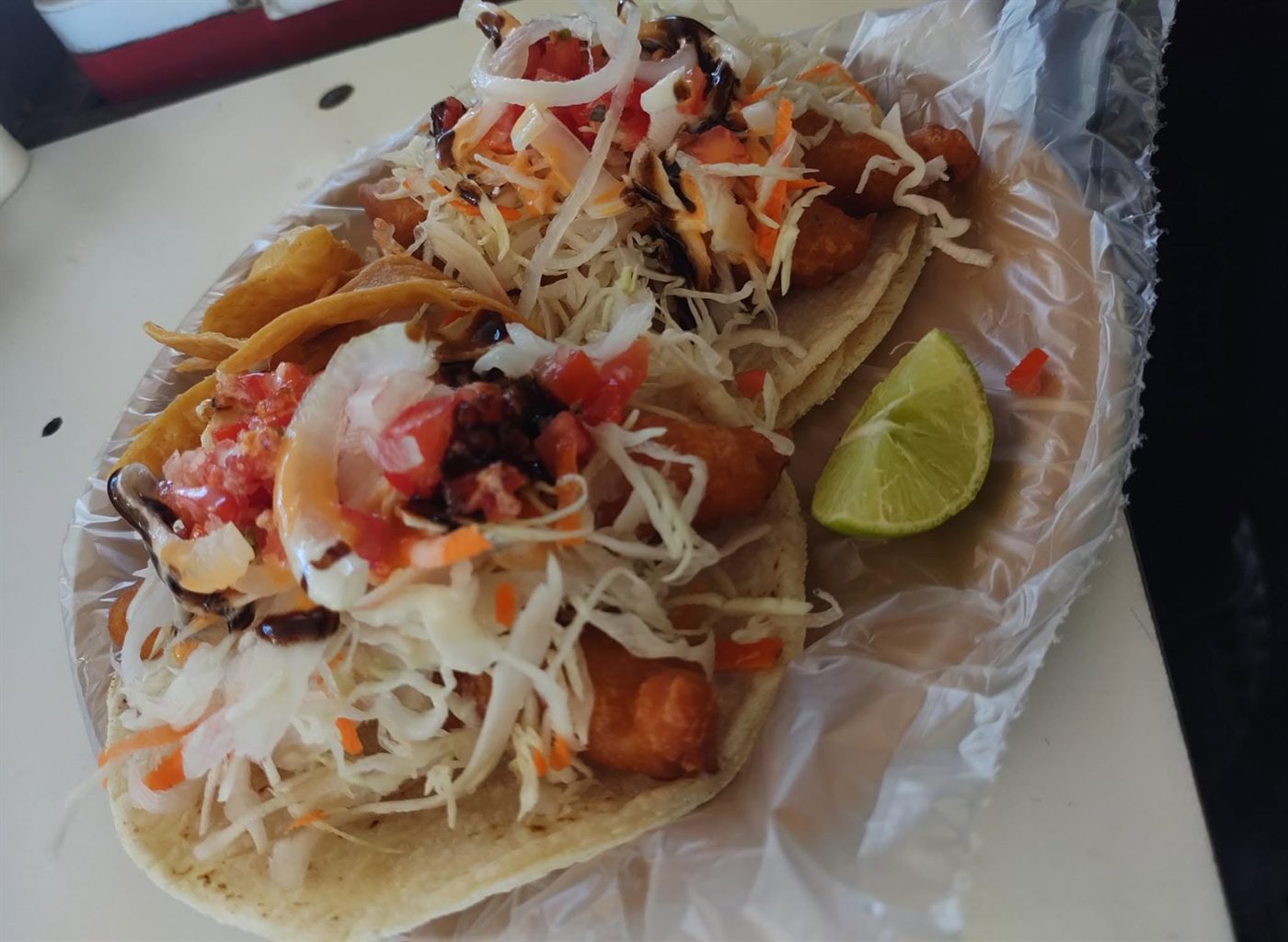 Tacos de pescado capeado con col, jitomate, cebolla y limón